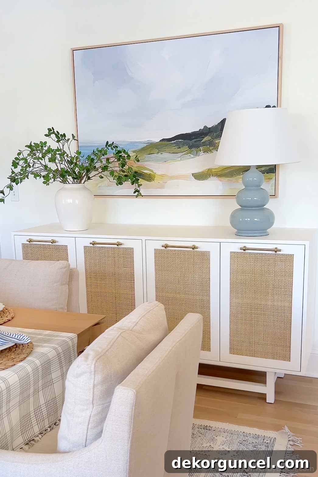 Dining room sideboard with table lamp, art, and vase with greenery