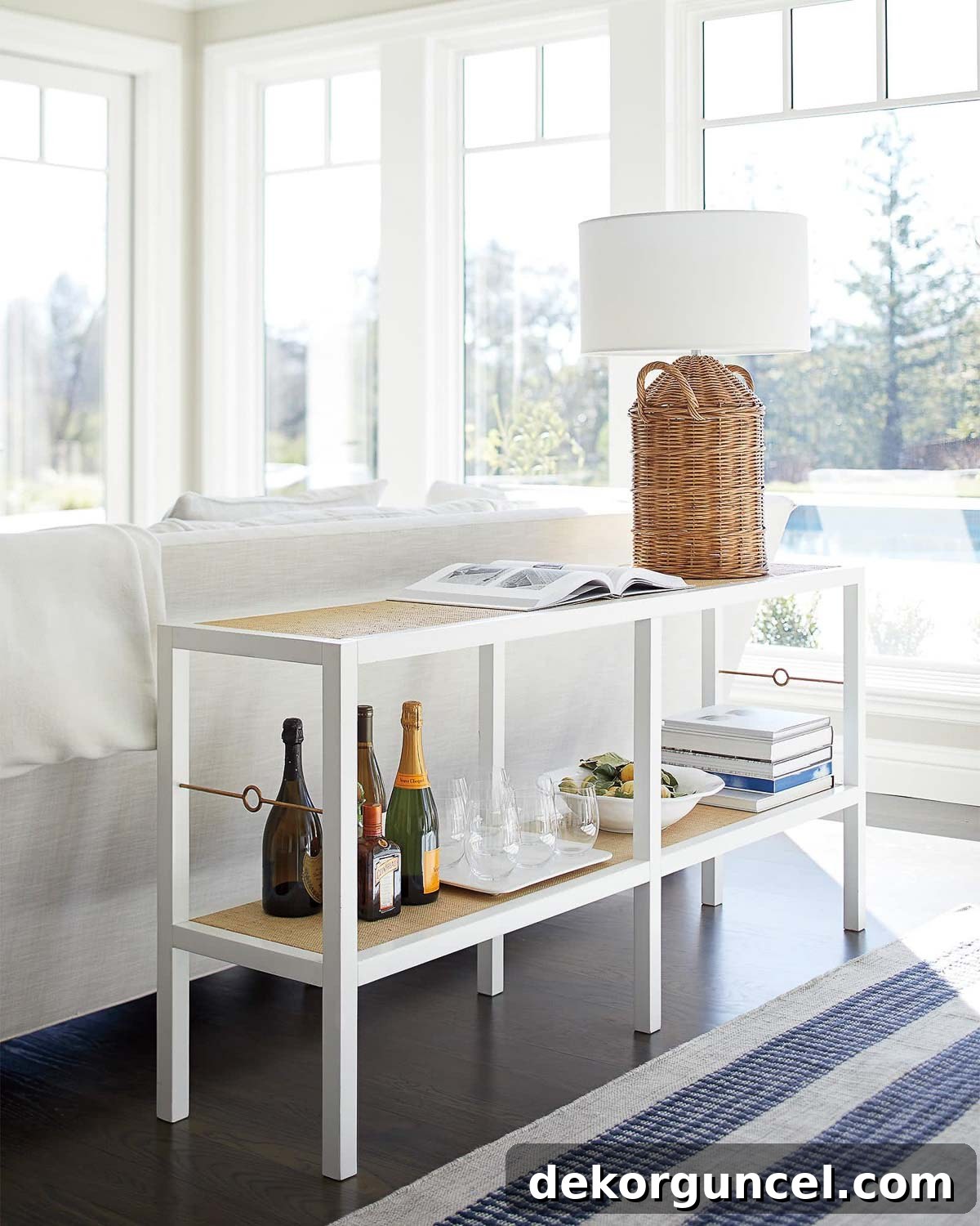 Simple white table behind sofa with raffia wrapped shelves and brass detailing
