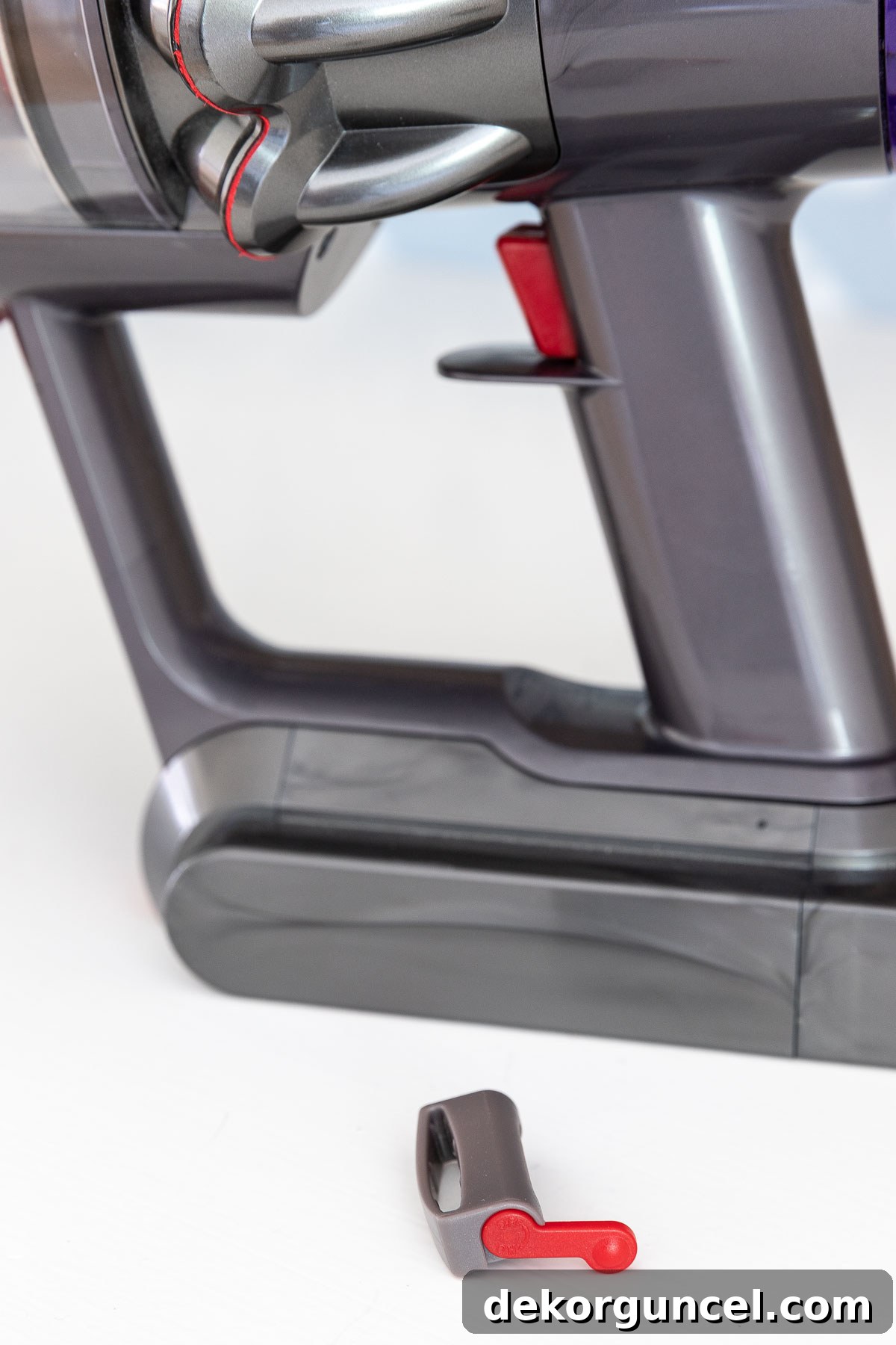 Dyson vacuum with small clamp slid onto trigger, showing the 'off' position with red lever up