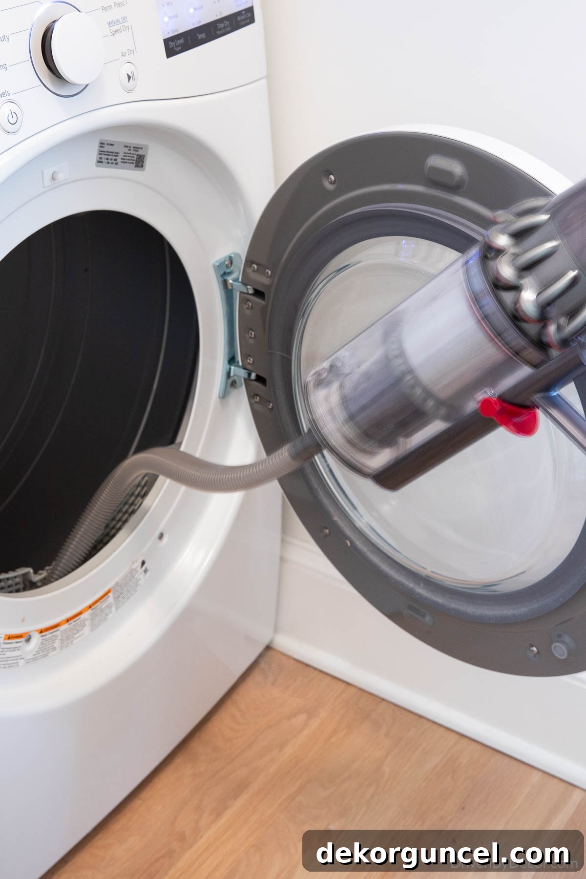 Dyson handheld vacuum with a long, flexible attachment being used to clean lint from a dryer vent