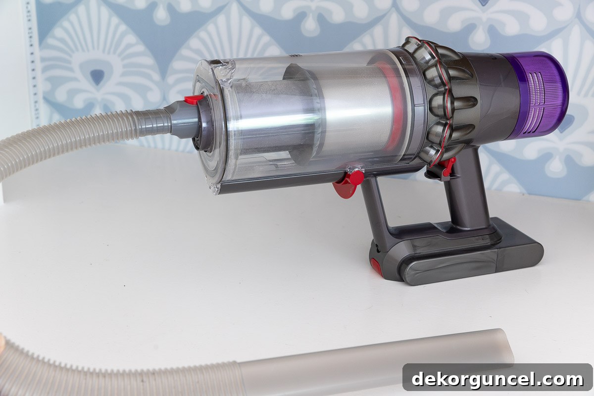 Dyson handheld vacuum with a long, flat attachment demonstrating its reach for cleaning under furniture