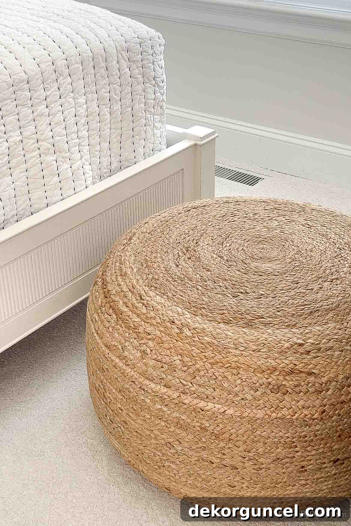 Large jute pouf serving as coastal bedroom decor at the foot of a twin bed, adding warmth and natural texture