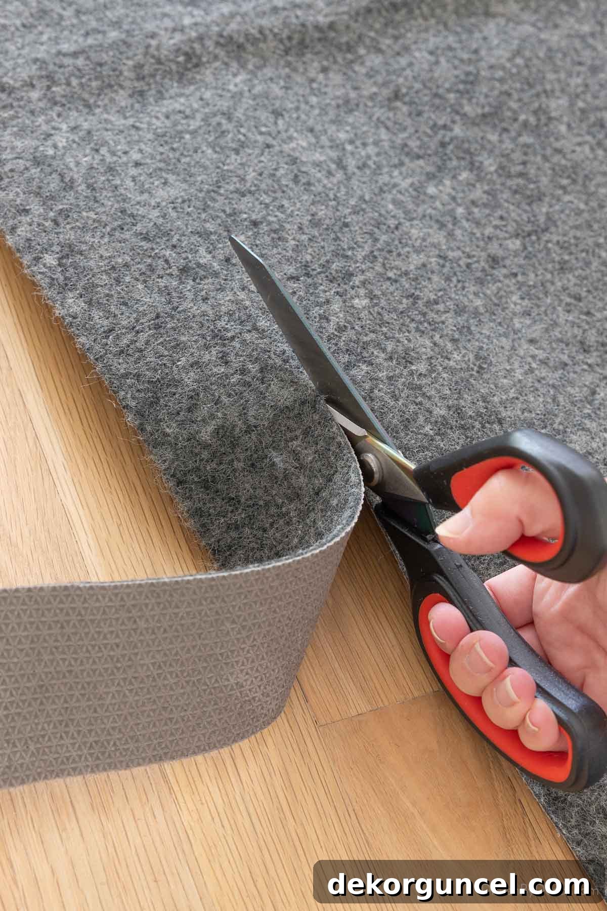Person cutting a rug pad with sharp scissors along a marked line