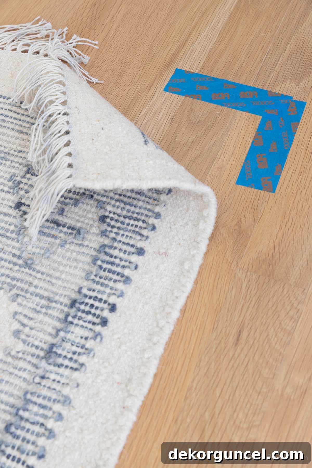 Corner of a rug marked with painter's tape on a hardwood floor