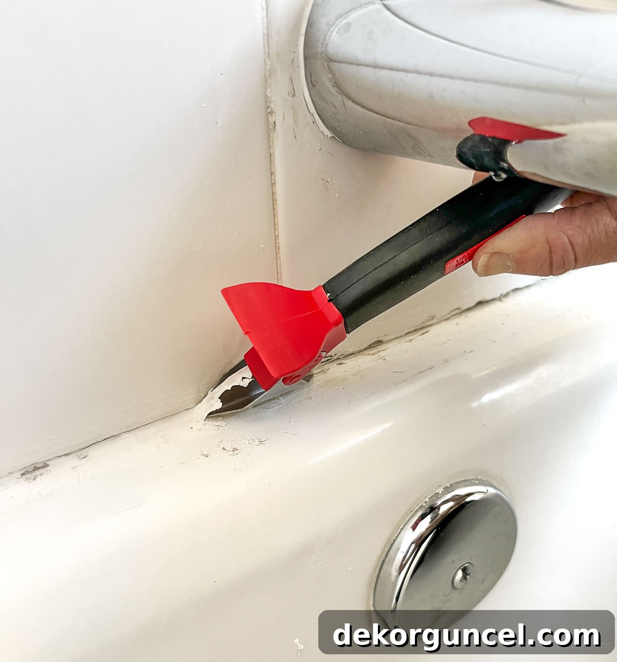 Removing old caulk from bathtub with a specialized removal tool