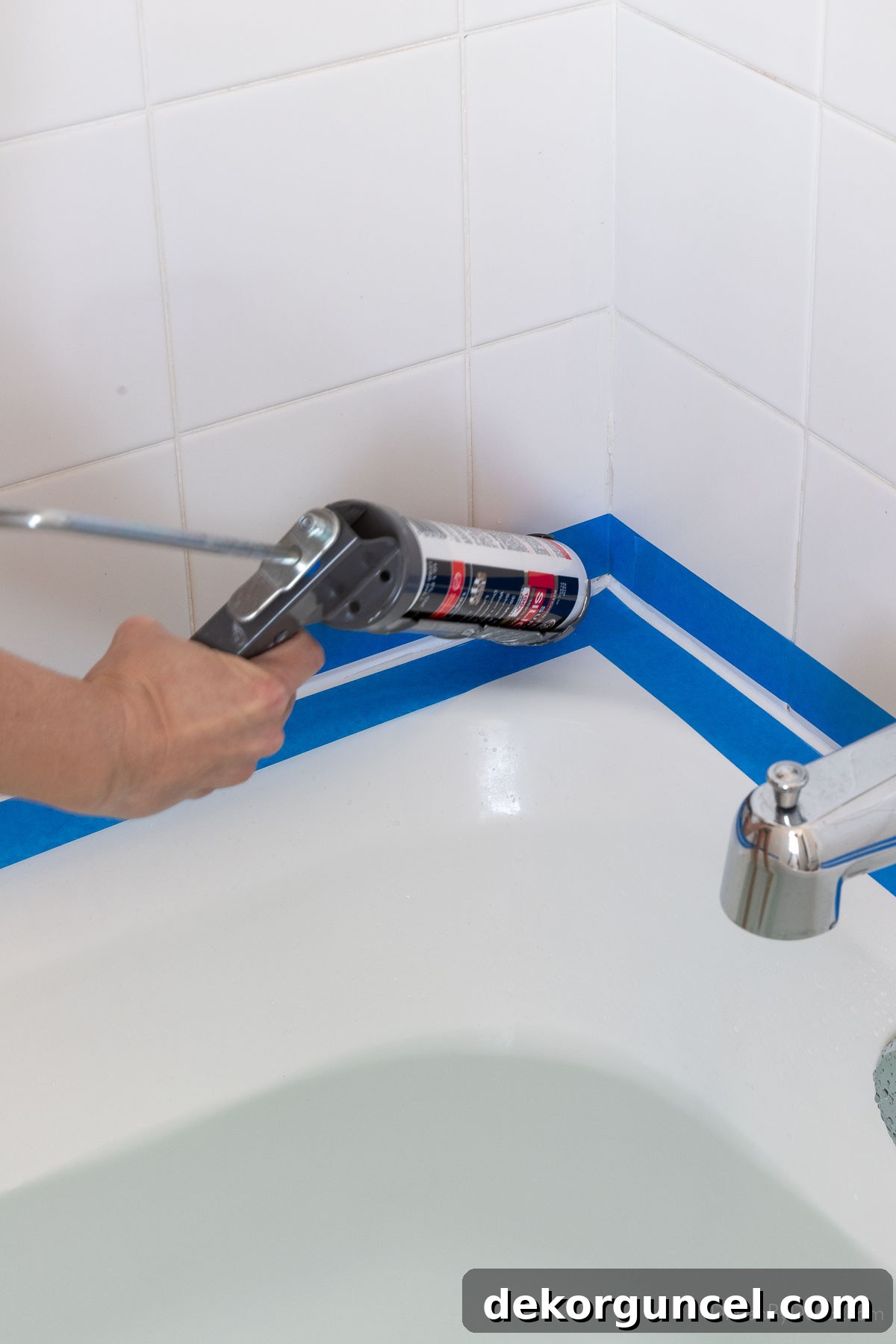 Applying caulk to a bathtub joint with a caulk gun