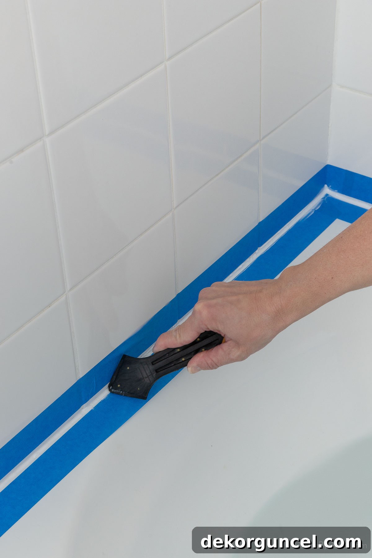 Using a caulk finishing tool to smooth out the caulk line around a bathtub