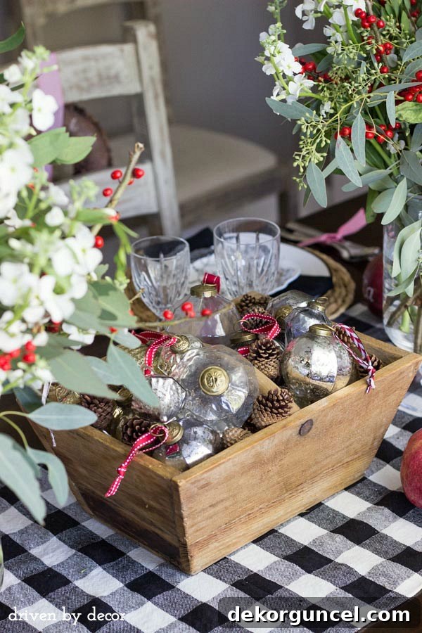 Christmas table centerpiece of glass and metallic ornaments mixed with pine cones