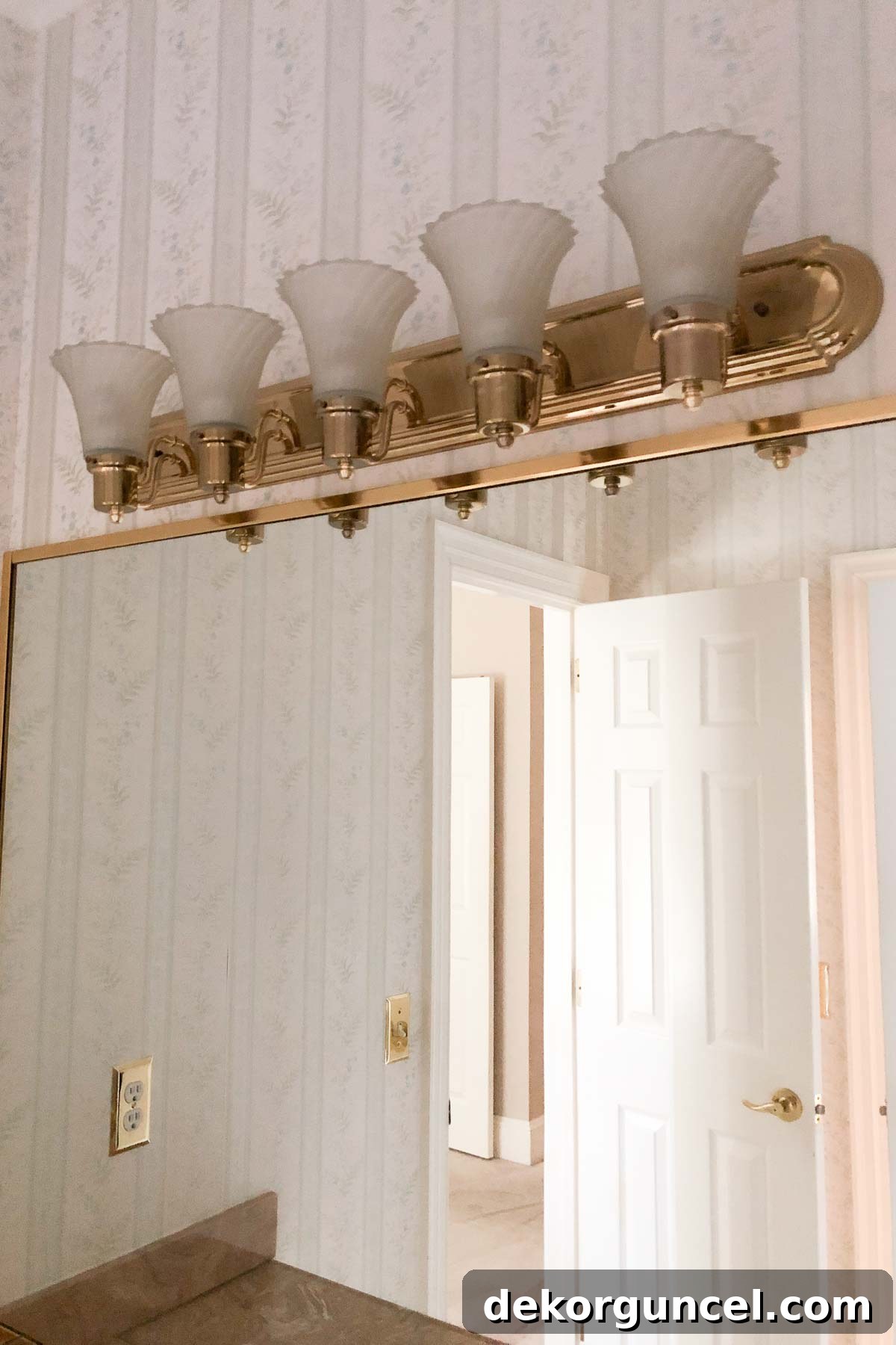 Bathroom mirror and lights before the remodel, showing outdated fixtures and a single large mirror