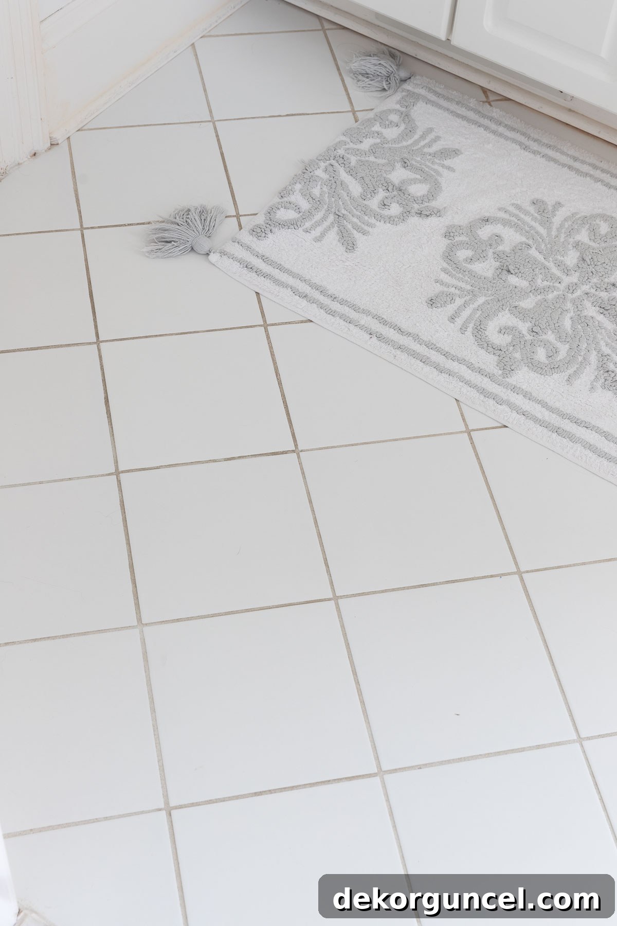 Old, chipped square bathroom floor tiles before the renovation, showing significant wear