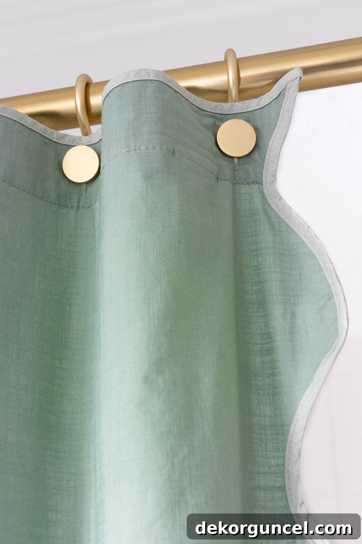 Close-up detail of stylish gold button shower hooks on a shower curtain, showing their unique design