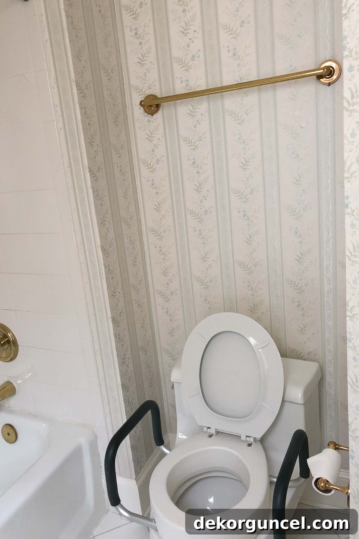 Old toilet before bathroom remodel, showing a towel bar awkwardly placed above it, highlighting the need for change