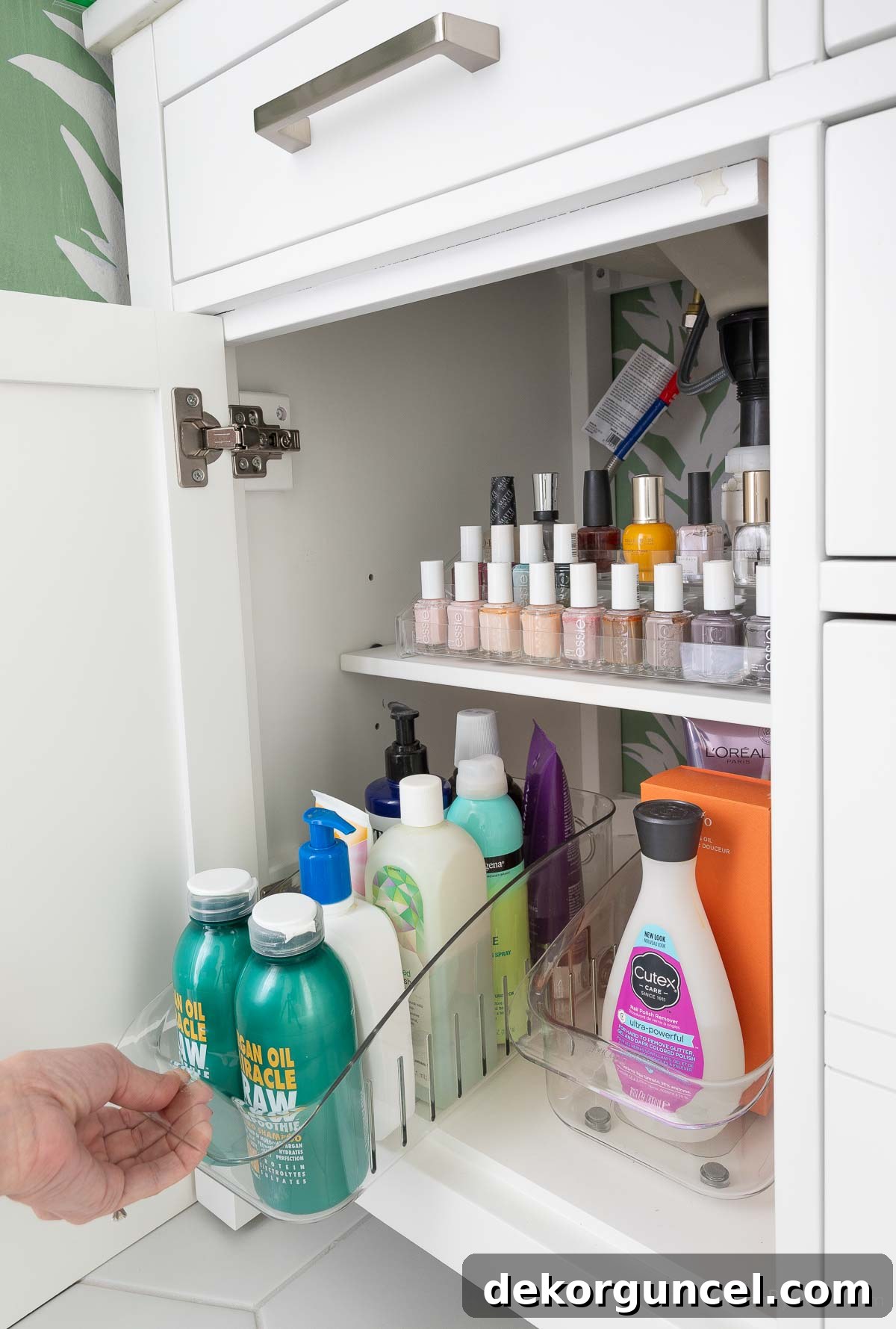 Organized storage space in one side of a double bathroom vanity cabinet, featuring acrylic and roll-out organizers for toiletries
