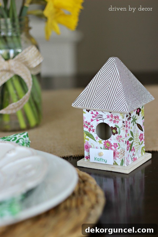 Dollar bin birdhouse covered with scrapbook paper holds name card for Easter table