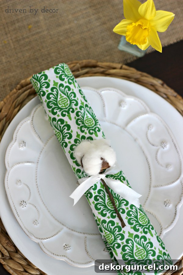 Simple spring place setting with cotton stem tied onto rolled napkin