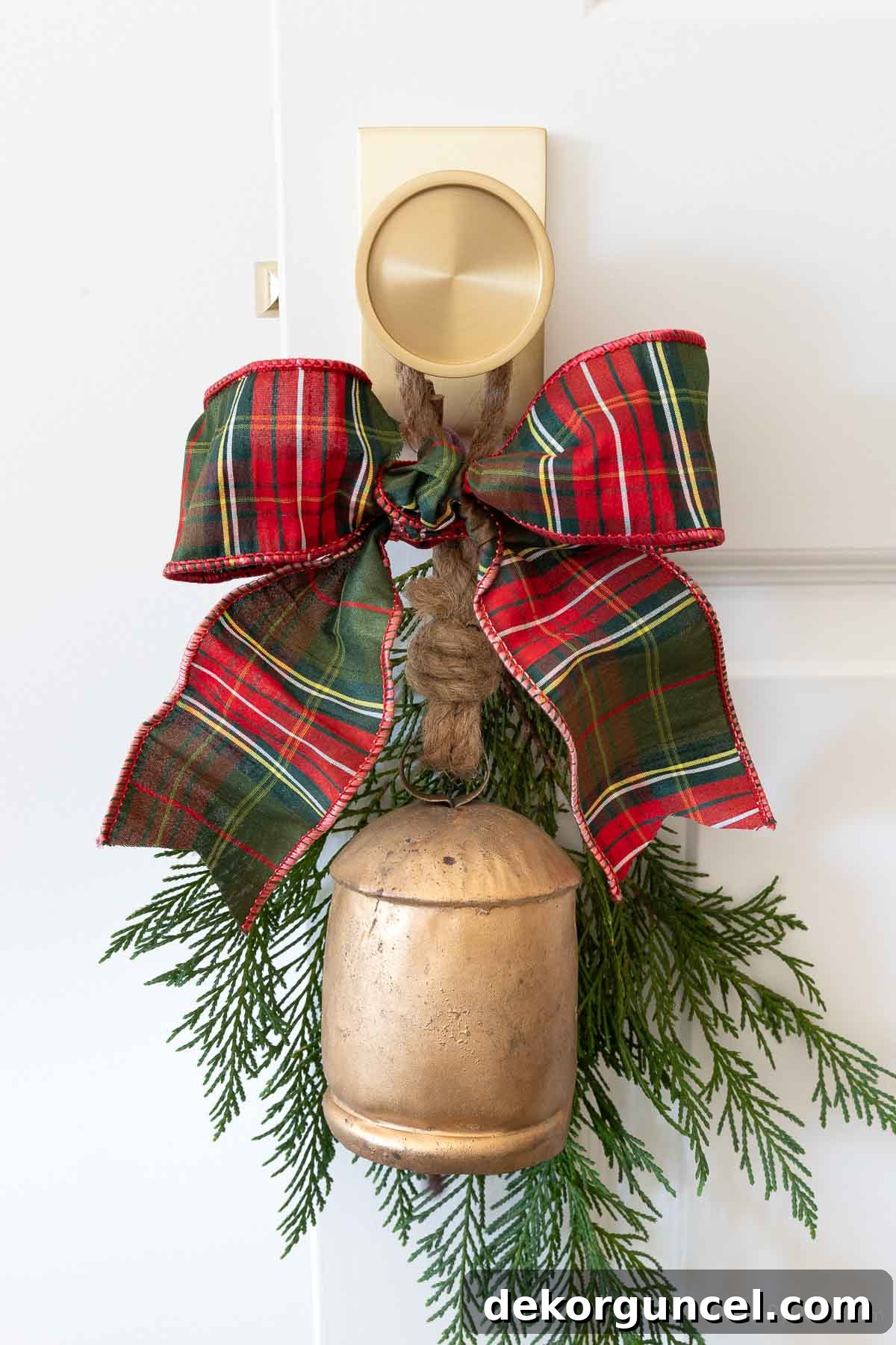 Charming holiday bell with fresh greenery and a bow adorning a doorknob