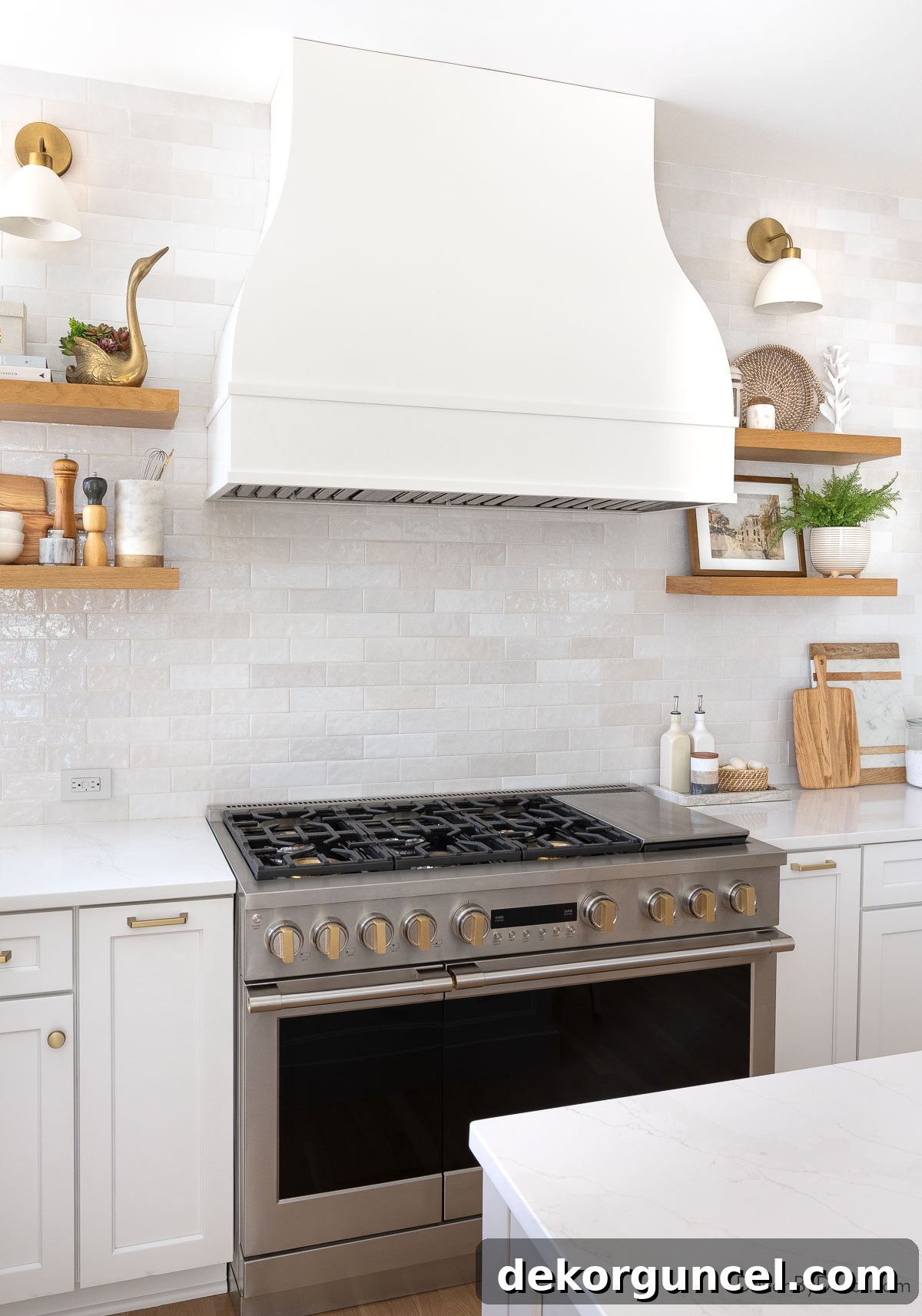 Elegant kitchen range and bell-shaped hood flanked by floating wood shelves and sconces, creating a balanced focal point