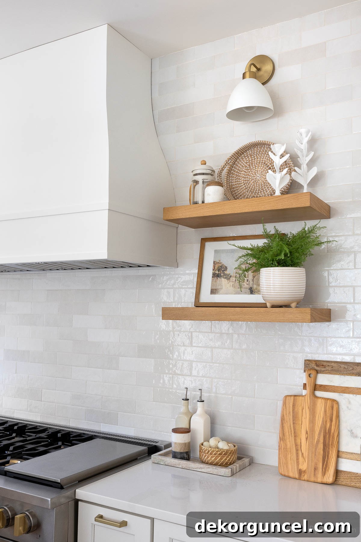 A chic brass and matte white sconce positioned above floating wood shelves in the kitchen, providing ambient lighting