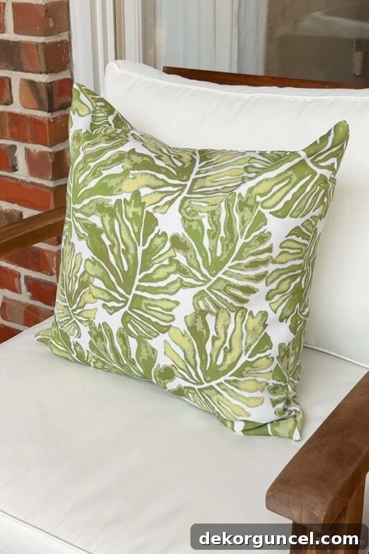 Green palm leaf outdoor pillow on chair for seasonal refresh