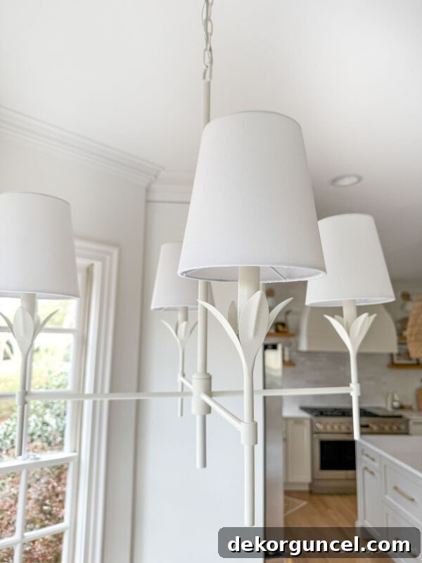 Matte white chandelier with linen shades over our kitchen table with petal design