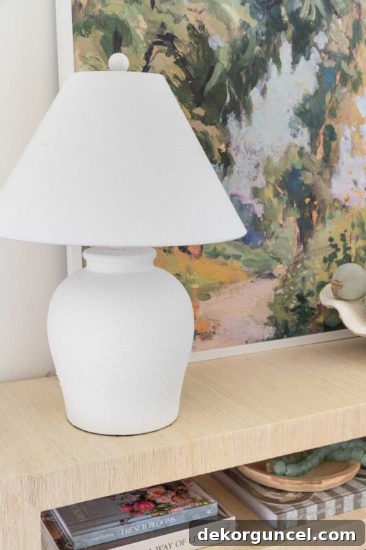 White lamp with modern tapered shade, adding texture to entryway console
