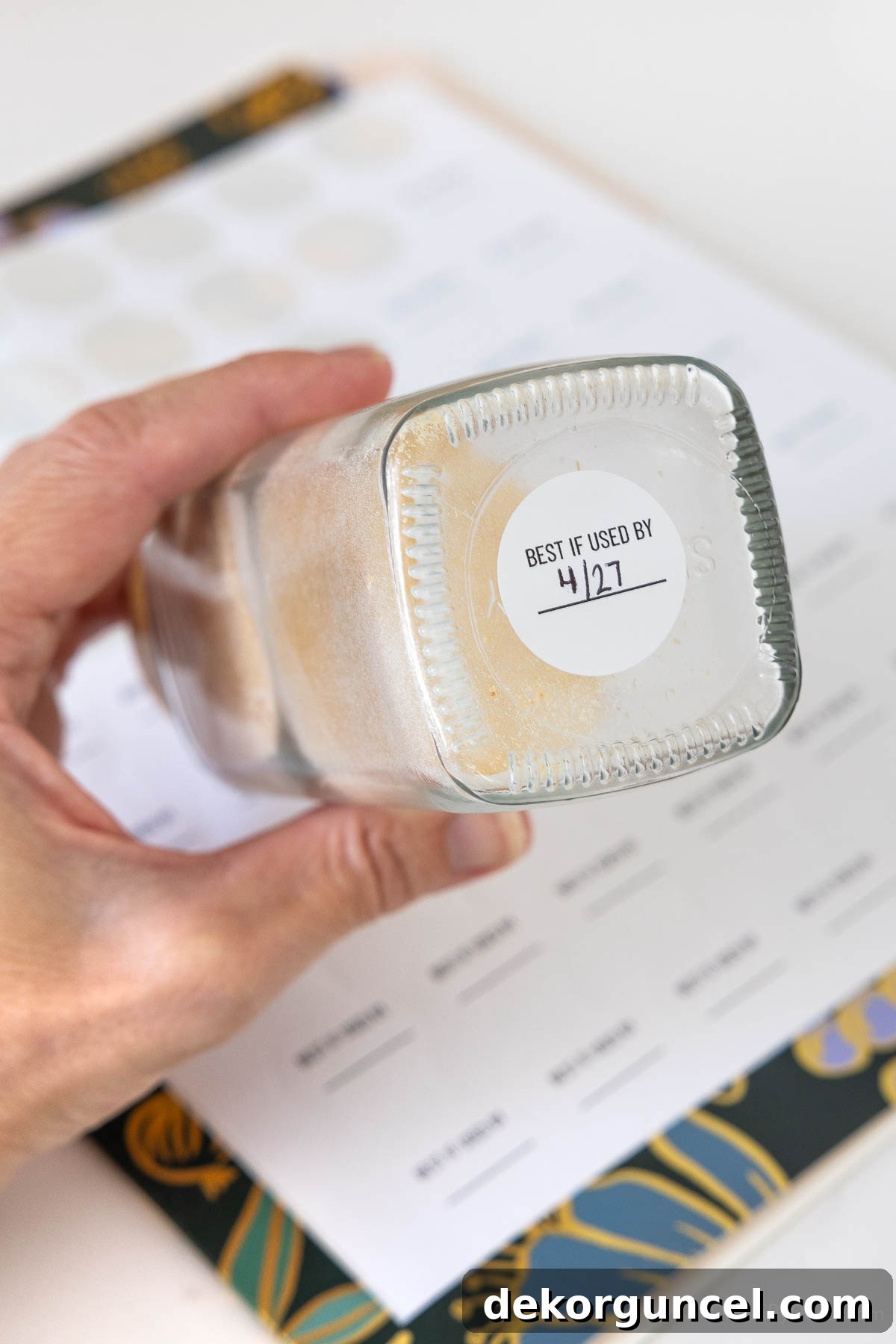 Small circular labels on the bottom of spice jars indicating expiration dates for freshness tracking.