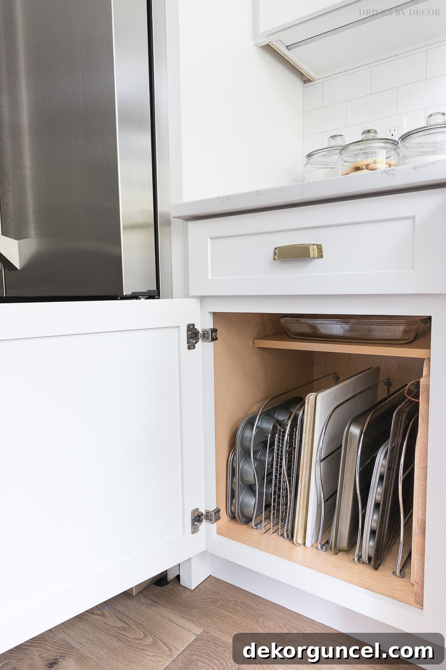 Metal tray dividers installed in a kitchen cabinet, neatly organizing bakeware and cutting boards vertically.