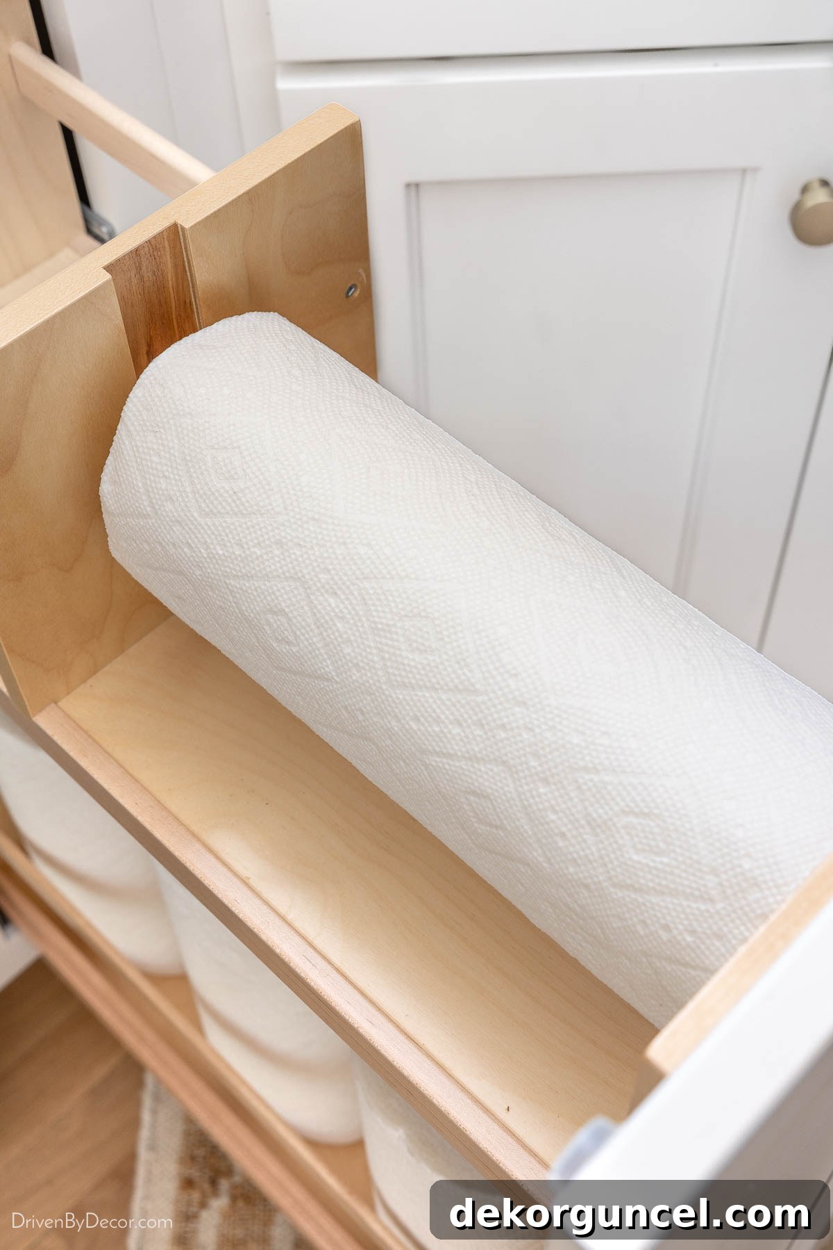 Close-up of a kitchen pull-out organizer with a built-in paper towel dispenser on the upper tier.