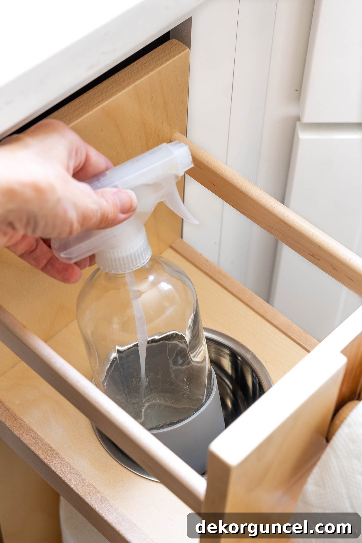 Kitchen cabinet pullout with a cleaning spray bottle stored below the paper towel roll.