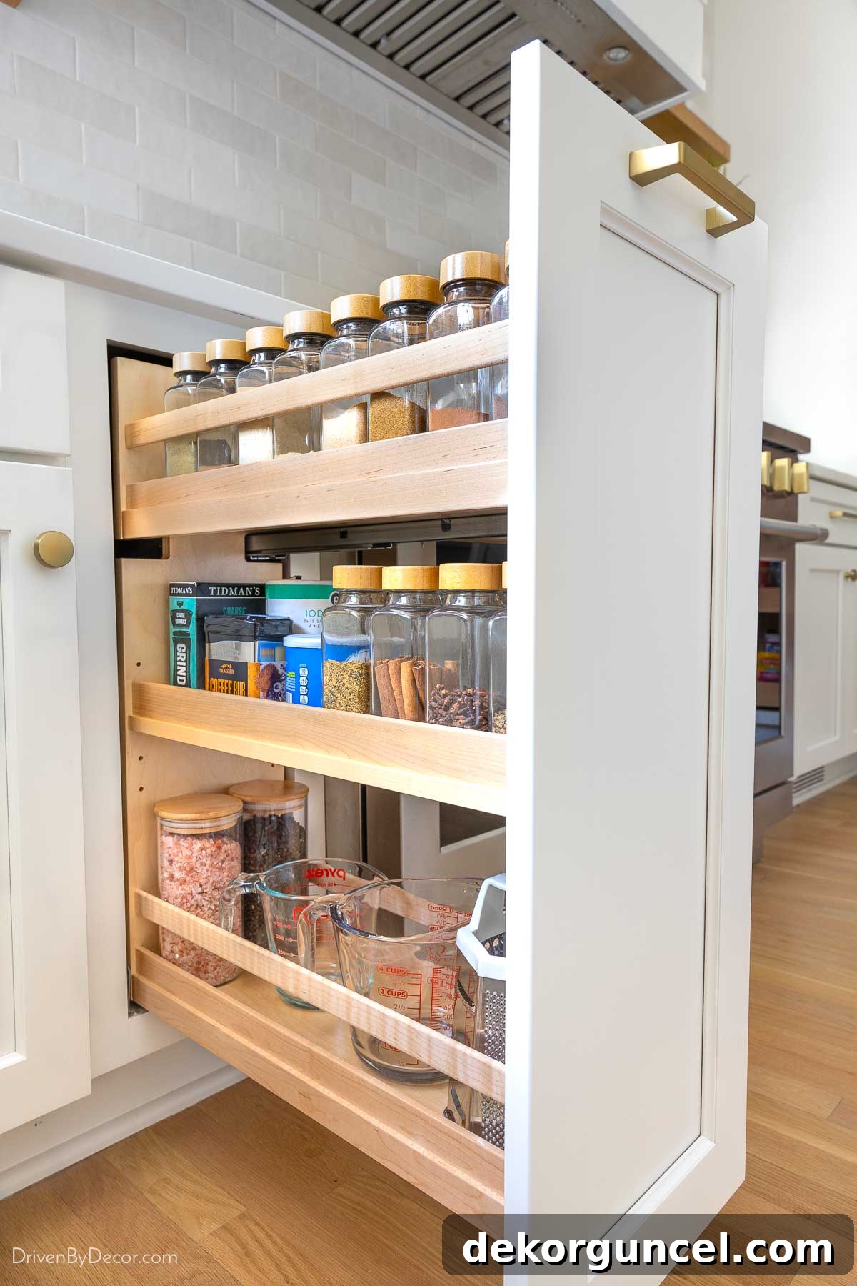 Kitchen cabinet pull-out spice rack with labeled jars for organized spice storage.