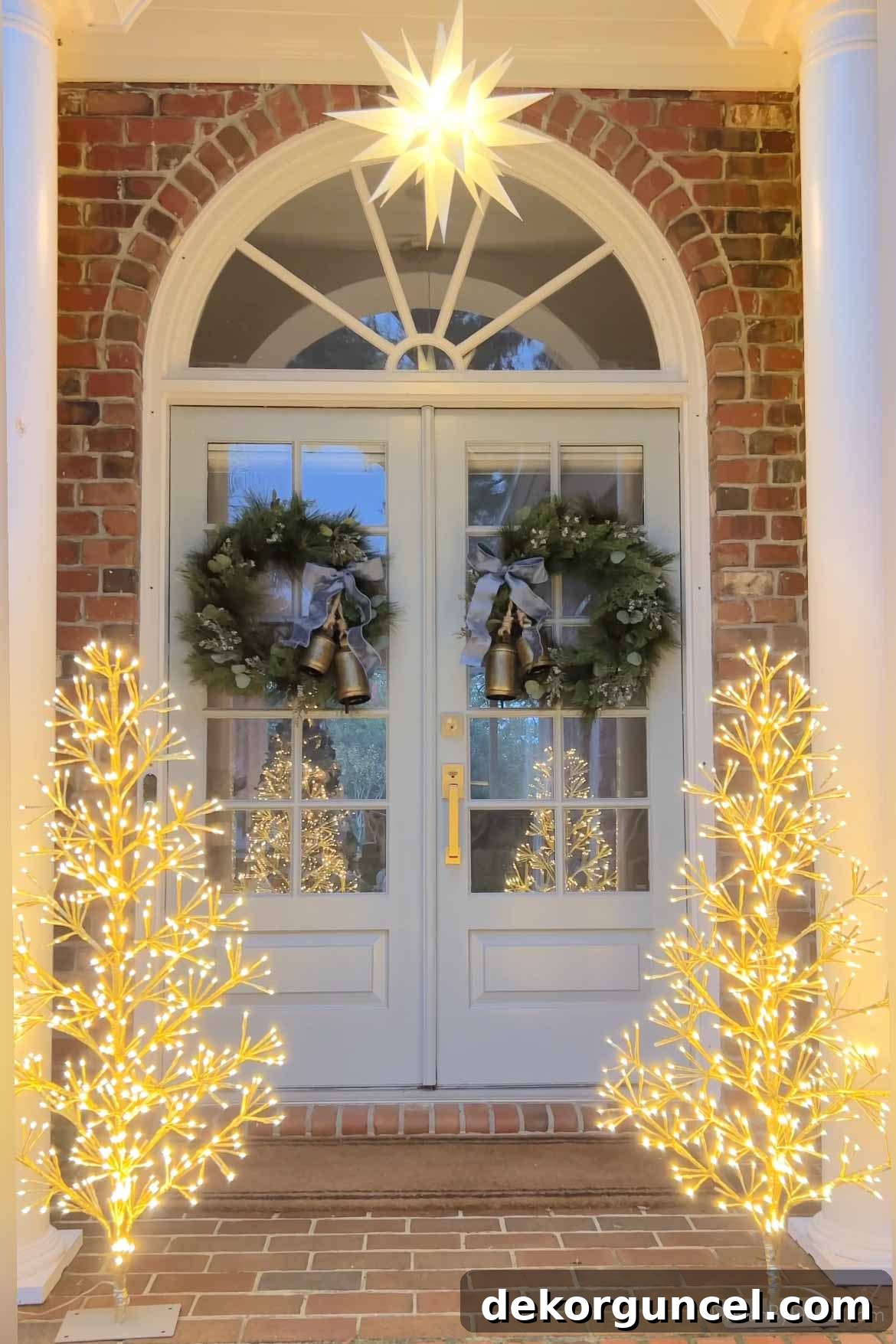 Pair of twinkling LED light trees and a hanging Moravian star on a front porch at Christmas