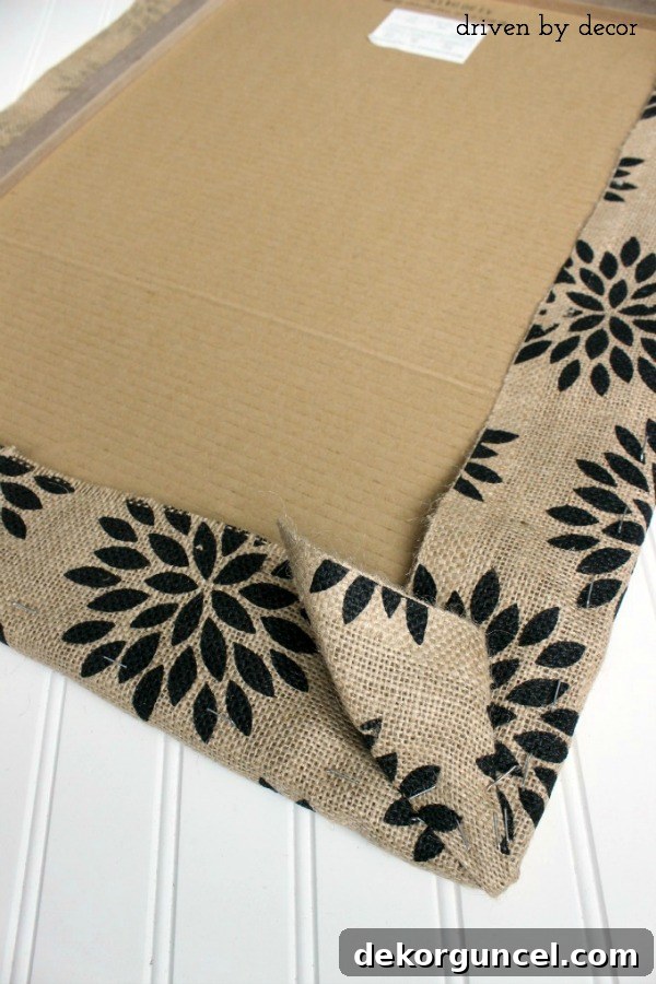 Step-by-step guide to neatly folding and stapling the corners of burlap for a covered bulletin board