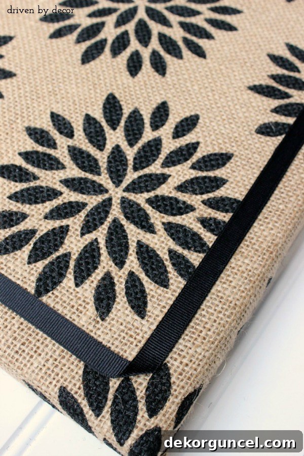 Handcrafted Burlap Pinboard 8 Applying grosgrain ribbon with glue dots to create a neat, decorative border on a burlap covered cork board