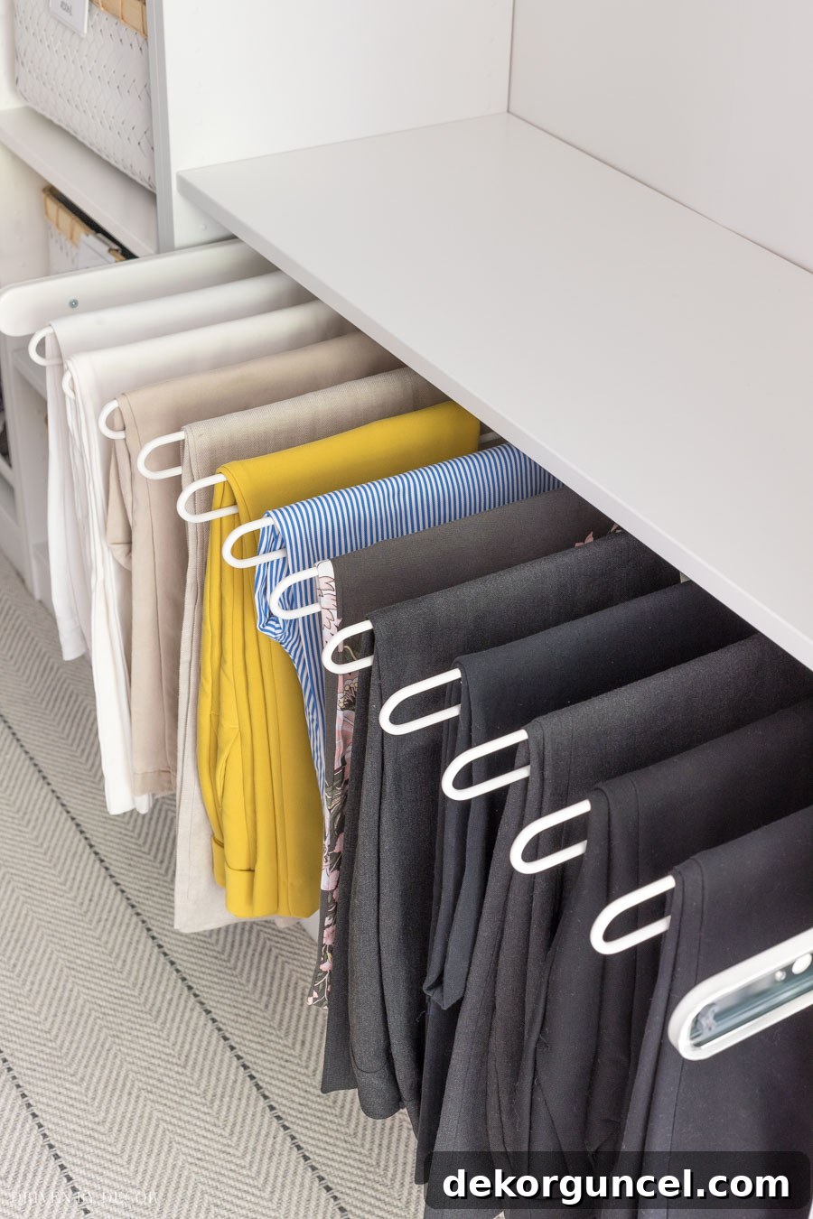 Neatly organized pants on an IKEA PAX KOMPLEMENT pull-out pants hanger, maximizing space in a walk-in closet.