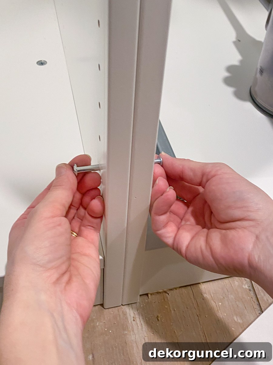 A close-up view illustrating how IKEA PAX wardrobe frames are securely attached using binding screws during installation.