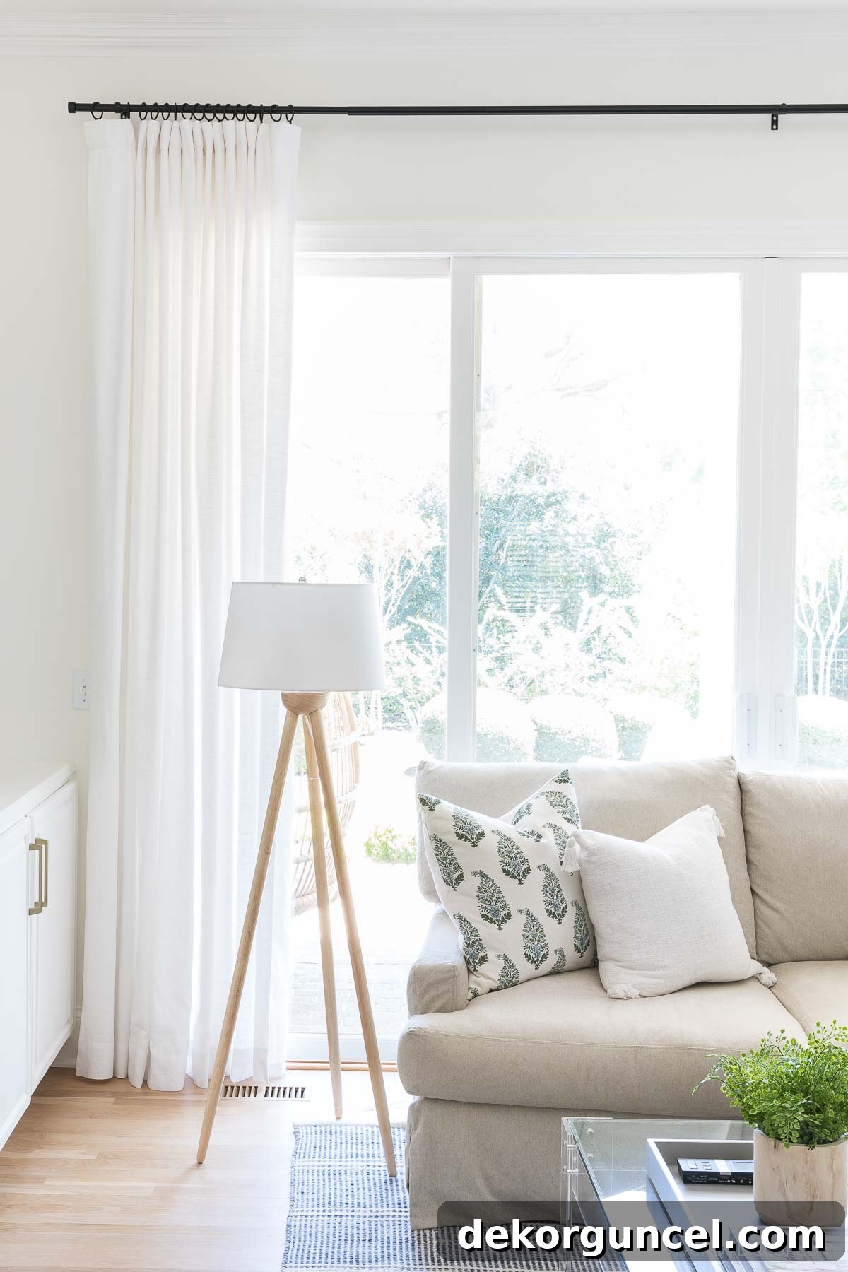 Elegant white drapes in a family room, showcasing the ideal height for window treatment installation to enhance space.