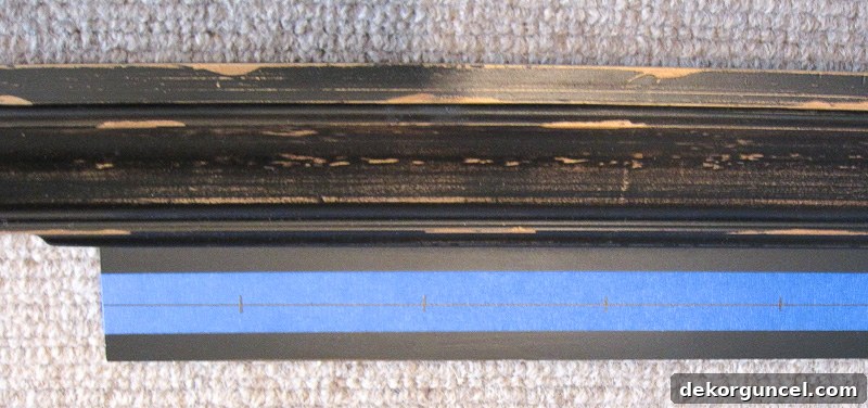Using painter's tape to precisely mark drilling spots for evenly spaced knobs on a ledge shelf.