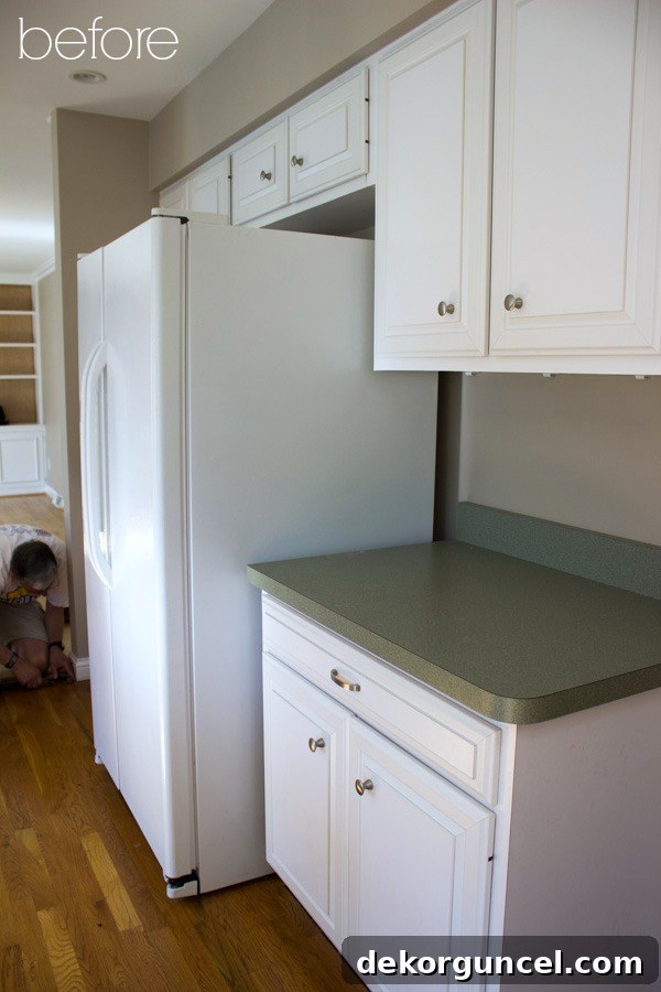 Before photo showing the old refrigerator extending beyond the cabinet line, hindering kitchen flow, next to existing cabinets.