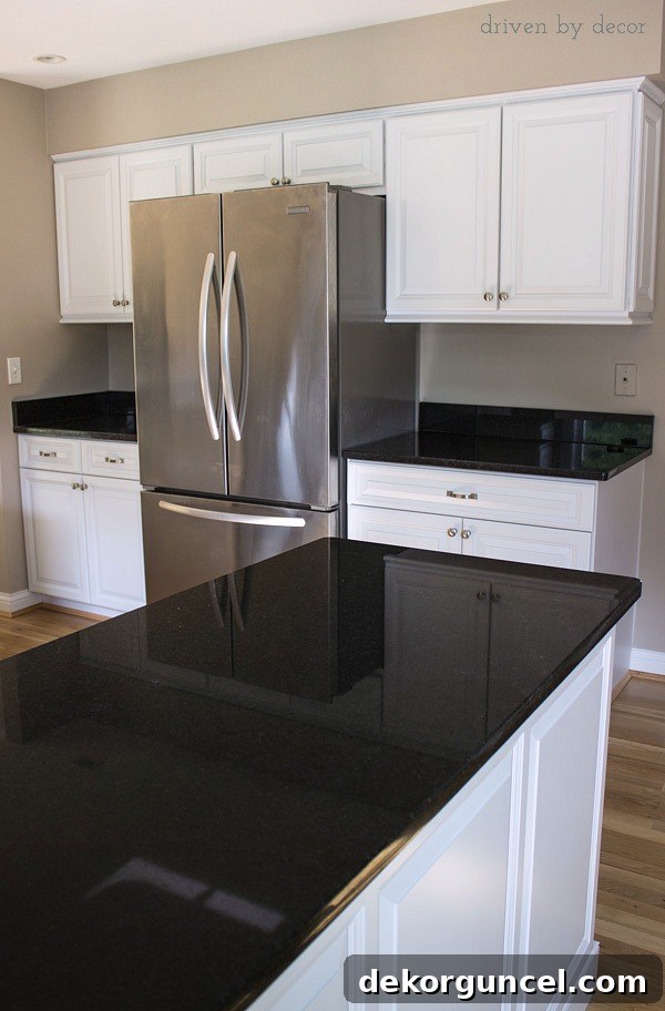 After photo showcasing a beautifully remodeled kitchen with newly refaced cabinets, a counter-depth KitchenAid refrigerator seamlessly integrated, and elegant Black Pearl granite countertops.
