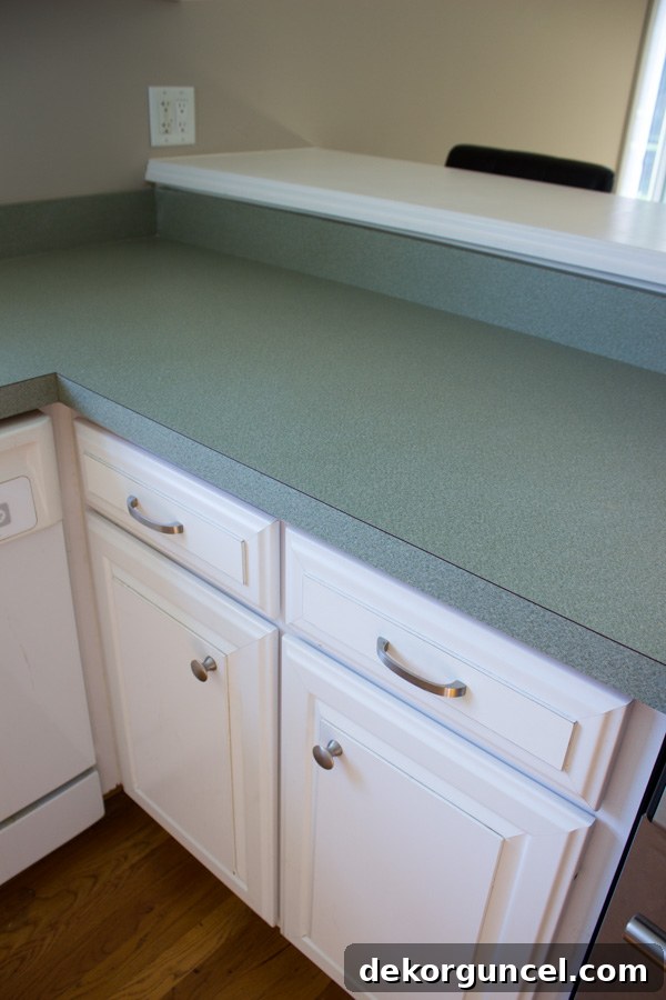 Before photo of a kitchen with outdated mint green laminate countertops and old cabinets, highlighting the need for a modern update.