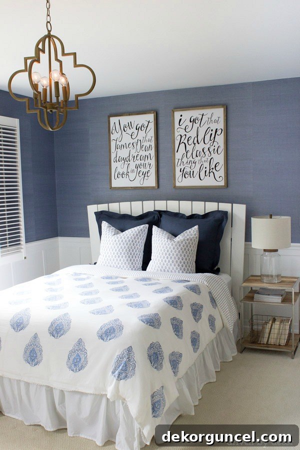 Modern coastal bedroom makeover with quatrefoil chandelier, grasscloth wallpaper, wood and chrome nightstand, and blue and white bedding. Beautiful!