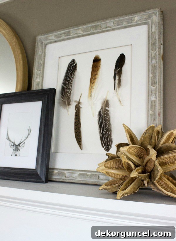 Layered artwork featuring a DIY feather piece and a deer print on a beautifully styled fireplace mantel