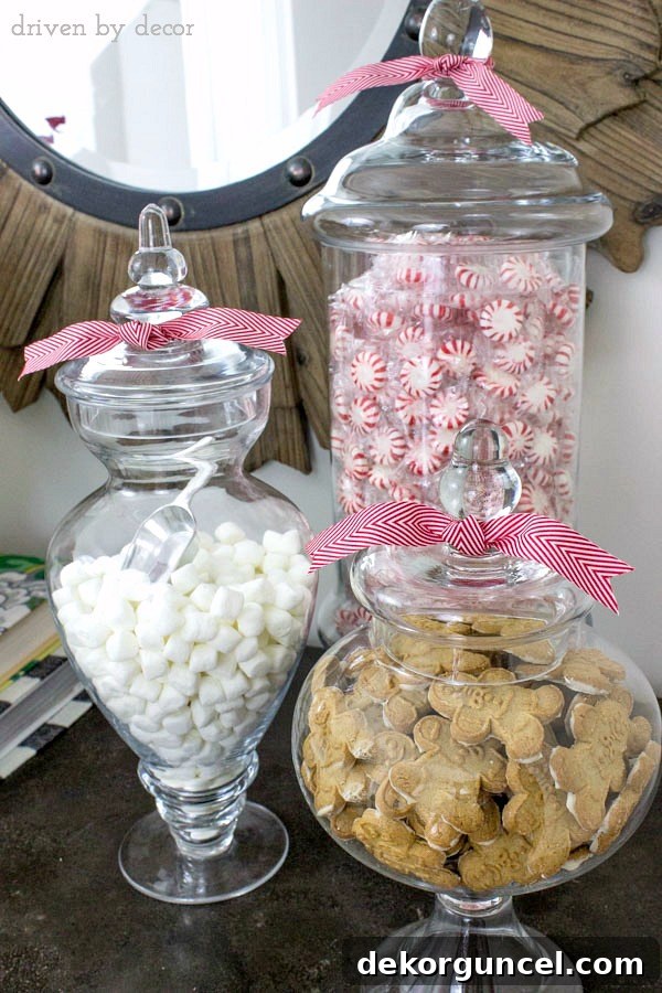 Quintessential New England Christmas Style 5 A close-up of apothecary jars filled with a tempting array of holiday treats including refreshing mints, fluffy mini marshmallows, and classic gingerbread men, perfect for festive snacking.