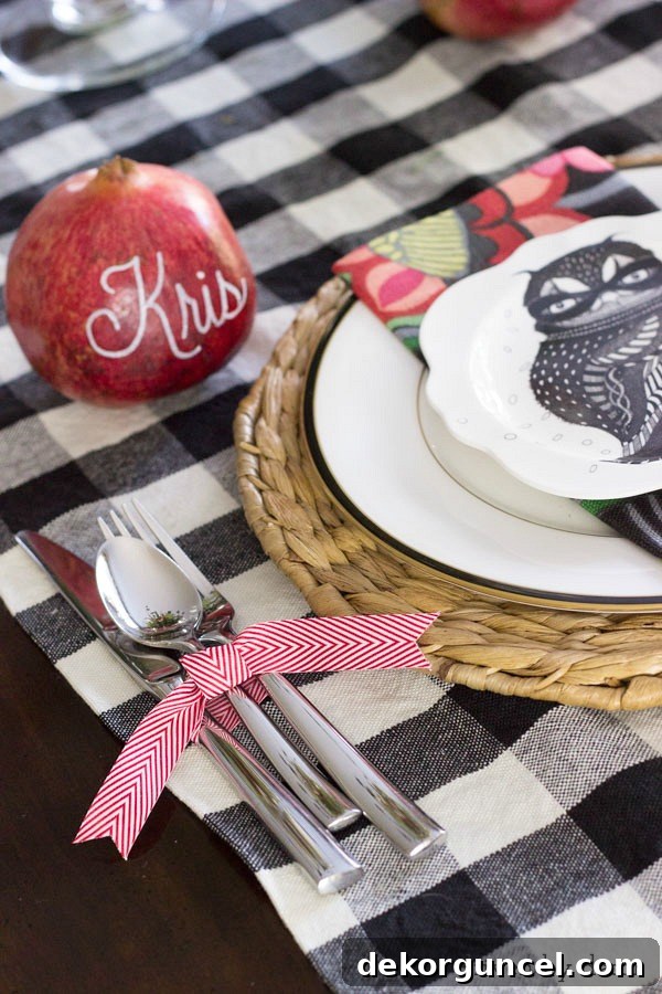 Quintessential New England Christmas Style 9 Creative place cards featuring guests' names beautifully written on real pomegranates with paint pens, alongside silverware elegantly tied with festive ribbon—a perfect, personalized touch for any holiday table setting.