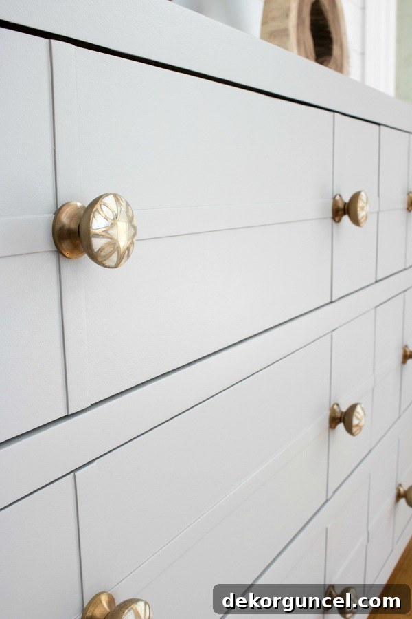 A bedroom dresser painted in Farrow & Ball's Worsted, a sophisticated greige shade, paired with elegant mother of pearl knobs, transforming it into a luxurious focal point.