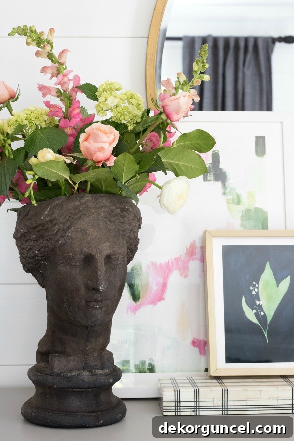 A charming and simple dresser vignette featuring a unique planter statue, a decorative box for added elegance, and two pieces of art thoughtfully layered to create visual interest and depth.