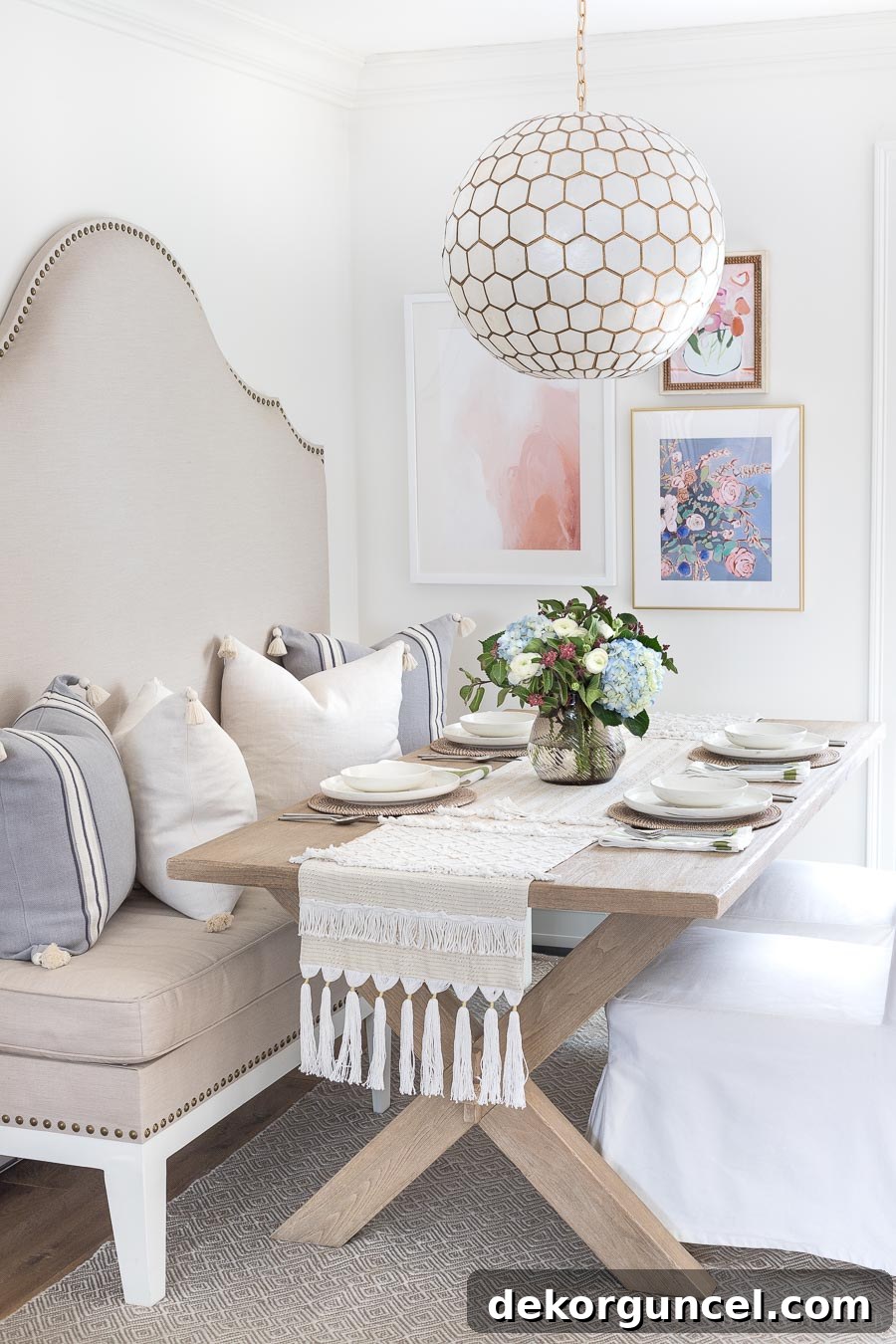 My Top 10 DIY Home Projects 14 A charming kitchen eat-in area featuring a custom DIY upholstered banquette with nailhead trim, a stylish capiz pendant, and a gallery wall with three coordinated art pieces, creating an inviting and chic dining space.