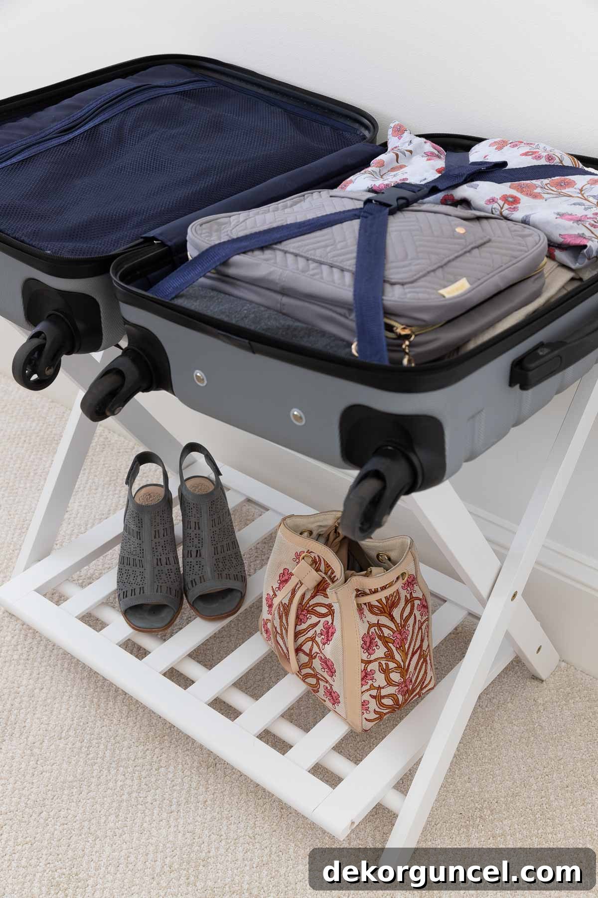Guest room featuring an open white luggage rack with a suitcase on top and additional storage on the lower shelf