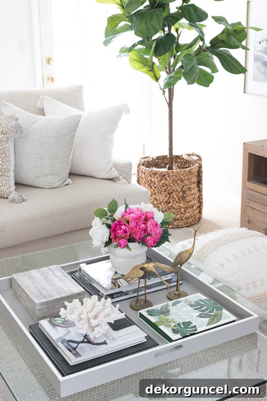 A large wood tray anchoring coffee table decor on an acrylic coffee table, showcasing effective styling tips.