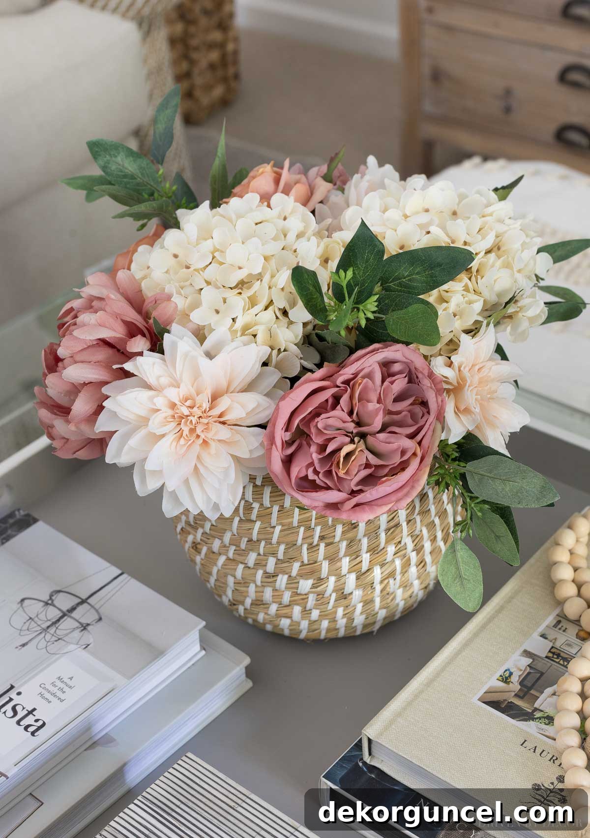 A lush arrangement of artificial flowers, including silk roses, dahlias, and hydrangeas, adorning a family room coffee table.